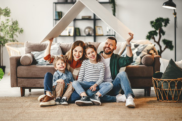 happy family sitting on floor holding up roof